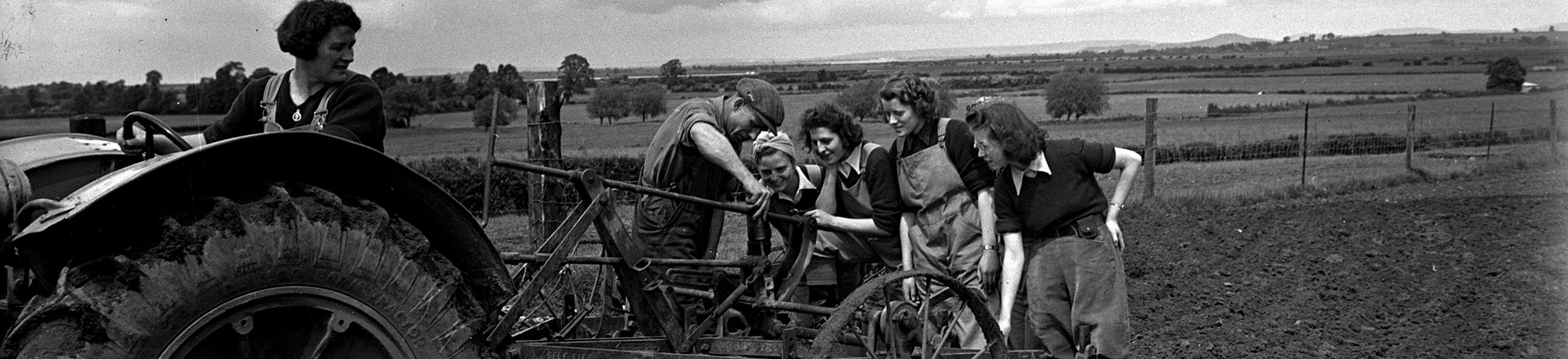 Plough attached to a tractor being demonstrated to land girls