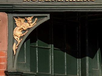 Fascia above entrance with carved gothic brace depicting a dragon.