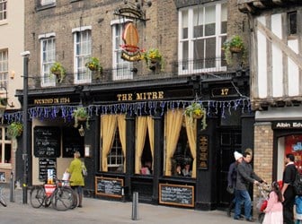 General view of the exterior of the Mitre Public House, Cambridge UK, with people walking past on the street