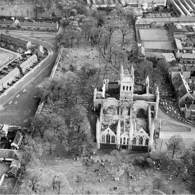 Aerial photo showing Great Yarmouth Minster and graveyard after bombing during the Second World War. The minster walls are standing but the roof has gone and inside is full of rubble.