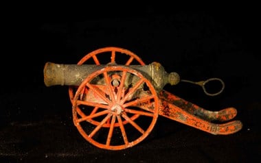 Toy cannon with carriage and wheels painted red
