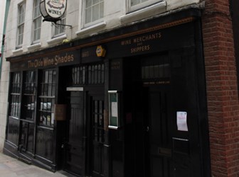 A photograph of a pub with a painted black wooden front. 