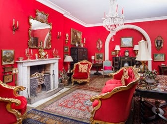 Interview view of a mostly red Regency-style drawing room within a manor house