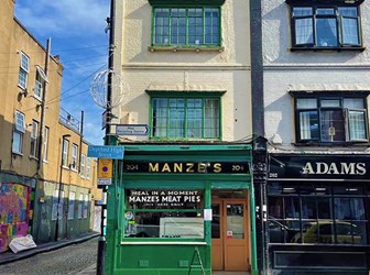 A green historic shop front with lettering saying "Manze's" and "Manze's meat pies".